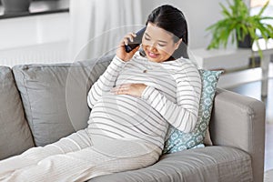 happy pregnant woman calling on smartphone at home