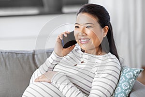 happy pregnant woman calling on smartphone at home