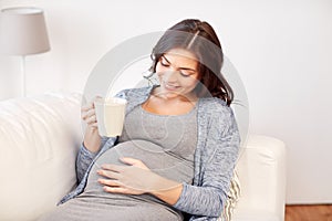 Happy pregnant woman with cup drinking tea at home