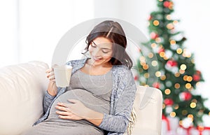 Happy pregnant woman with cup drinking tea at home
