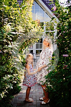 Happy pregnant woman with daughter in garden