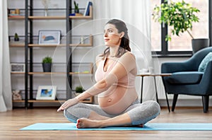 Happy pregnant woman doing yoga at home