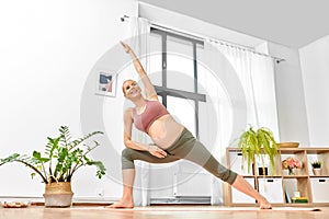 Happy pregnant woman doing yoga at home