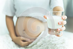 Happy pregnant woman drinking a glass of fresh milk