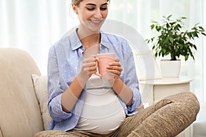 Happy pregnant woman drinking tea at home