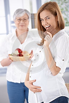 Happy pregnant woman eating chocolate