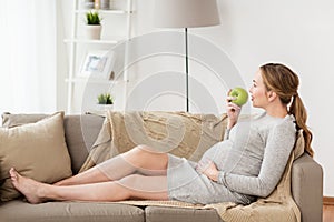 Happy pregnant woman eating green apple