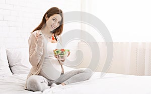 Happy pregnant woman eating natural vegetable salad