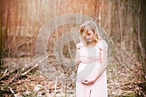 Happy pregnant woman enjoying walk in forest