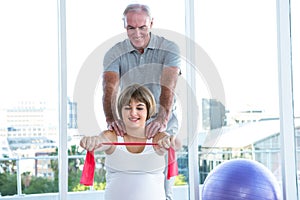 Happy pregnant woman exercising with resistance band