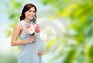 Happy pregnant woman with flowers touching belly