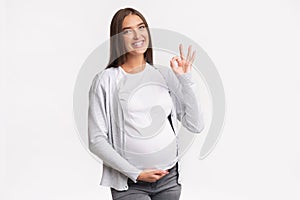 Happy Pregnant Woman Gesturing Okay Standing Over White Background