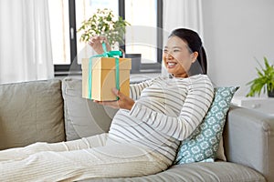 happy pregnant woman with gift box at home