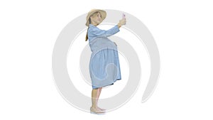 Happy pregnant woman in a hat using her smartphone doing selfie
