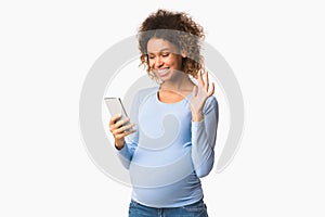 Happy pregnant woman having video call and waving hand