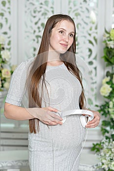 Happy pregnant woman with headphones on belly posing