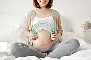 Happy pregnant woman with headphones at home