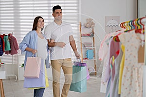 Happy pregnant woman and her husband with shopping bags in store