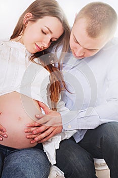 Happy pregnant woman with her husband touching her belly with hands