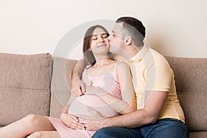 Happy pregnant woman and her husband waiting for baby at the home. happy family love and care concept