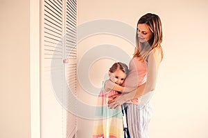 Happy pregnant woman with her toddler daughter at home