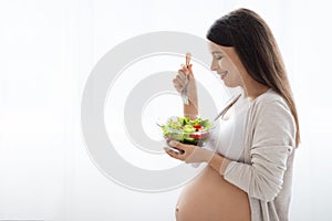 Happy pregnant woman holding bowl with fresh vegetable salad