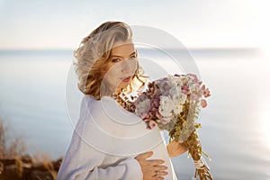 Happy pregnant woman holding a bunch of autumn flowers