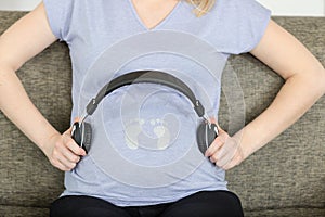 happy pregnant woman holding headphones