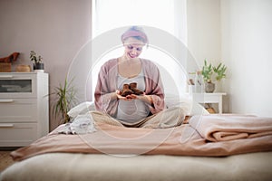 Happy pregnant woman holding little shoes for her baby.