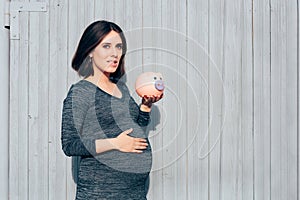 Happy Pregnant Woman Holding Piggy Bank