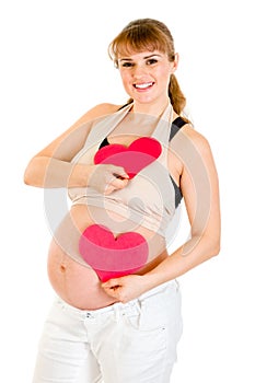 Happy pregnant woman holding two paper hearts
