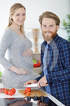 happy pregnant woman and husband mixing vegetables