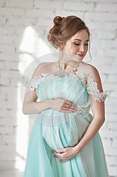 Happy Pregnant woman in long evening dress touching belly hands. Waiting the birth of a child, a woman in her eighth month
