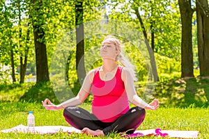 Happy pregnant woman in a lotus position doing yoga