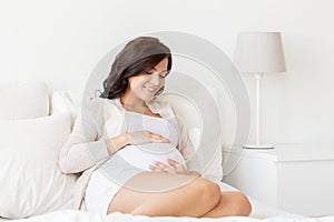 Happy pregnant woman lying on bed at home