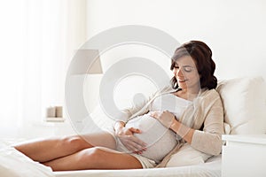 Happy pregnant woman lying on bed at home