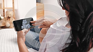 Happy pregnant woman lying on sofa and viewing child sonogram on display of smartphone, baby picture