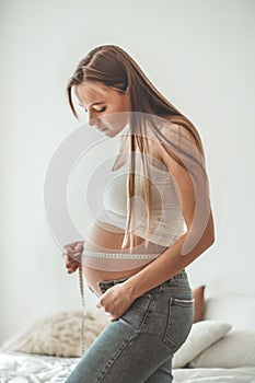 Happy pregnant woman with measuring tape Pregnancy, maternity, preparation and expectation concept