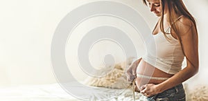 Happy pregnant woman with measuring tape Pregnancy, maternity, preparation and expectation concept