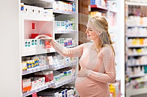 Happy pregnant woman with medication at pharmacy