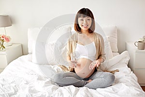 Happy pregnant woman with pills in bed at home