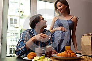 Happy pregnant woman preparing meals for husband