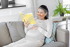 happy pregnant woman reading book at home