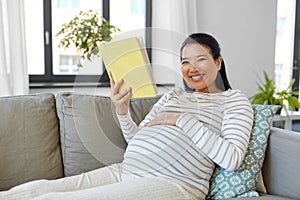 happy pregnant woman reading book at home