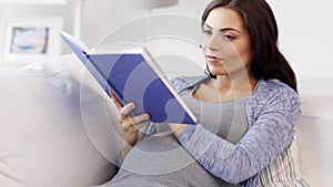 Happy pregnant woman reading book at home