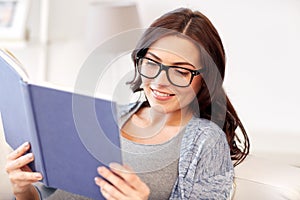 Happy pregnant woman reading book at home