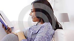 Happy pregnant woman reading book at home