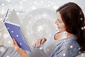 Happy pregnant woman reading book at home