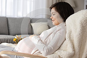 Happy pregnant woman relax in chair at home