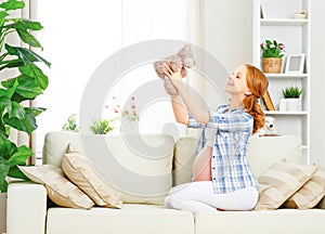 Happy pregnant woman relaxing at home with toy teddy bear